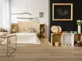 Jak pogodzić salon z sypialnią? Drewniane skrzynki, łóżko z drewnianym zagłówkiem i dekoracje w stylu rustykalnym tworzą przytulną przestrzeń.