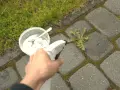 Domowy sposób na chwasty: ręka trzymająca spryskiwacz z roztworem, obok miseczka z sodą i łyżeczka.