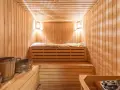 Przytulna sauna w domu, z drewnianymi ławami, wiaderkami i kamiennym piecem. Idealne miejsce na relaks.