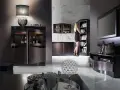 Eleganckie meble z drewna wenge: barek z lampą, regał z książkami, szafka RTV i witryna. Kobieta w czarnej sukience wybiera książkę.