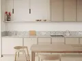 Jasna kuchnia z frontami w kolorze kaszmirowym, blatem z terrazzo i drewnianymi meblami.
