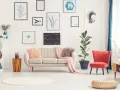 Sofa w kolorze ecru jaki to kolor? Delikatna, przytulna, idealna do salonu. Obok niej czerwony fotel i mnóstwo obrazów na ścianie.