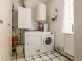 Pomieszczenie gospodarcze z pralką, suszarką, bojlerem i szafą.