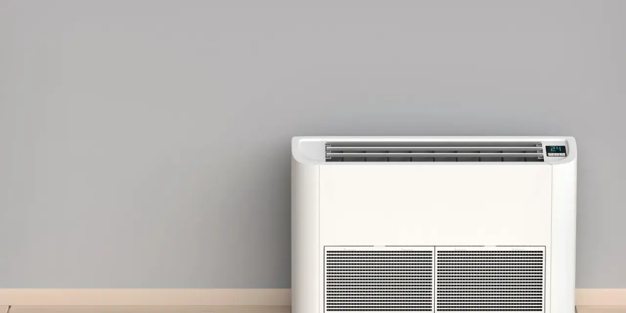 Nowoczesny klimatyzator bez jednostki zewnętrznej, stojący na drewnianej podłodze przy szarej ścianie.