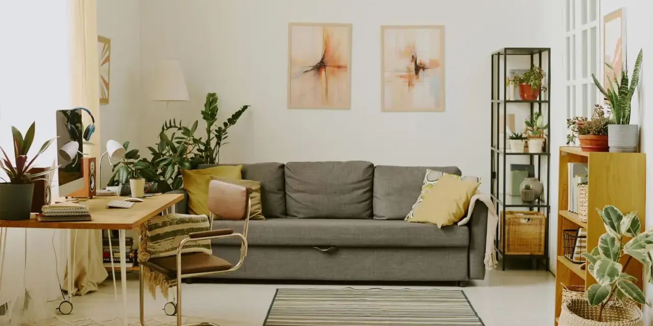 Przytulny salon z biophilic design: kanapa, biurko, rośliny i obrazy tworzą oazę spokoju.