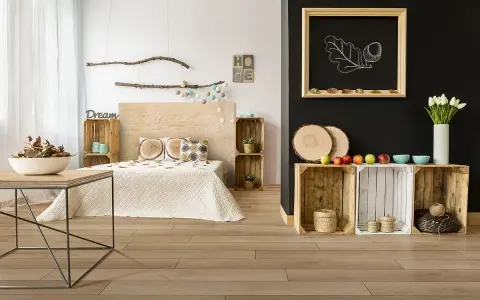 Jak pogodzić salon z sypialnią? Drewniane skrzynki, łóżko z drewnianym zagłówkiem i dekoracje w stylu rustykalnym tworzą przytulną przestrzeń.
