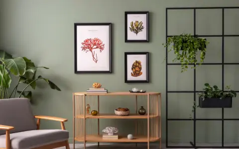 Salon z szarą sofą i drewnianą komodą, ozdobiony obrazami z motywami morskimi. Modne kolory ścian tworzą spokojną atmosferę.