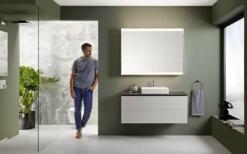 Nowoczesna wizualizacja łazienki z mężczyzną wchodzącym do strefy prysznicowej. Elegancka armatura, lustro z podświetleniem i minimalistyczna szafka pod umywalkę.