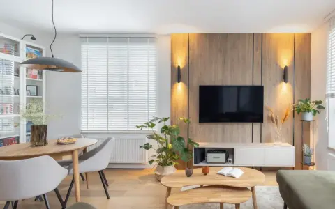 Przytulny salon inspiracje: drewniana ściana z TV, jadalnia, wygodne fotele i stoliki kawowe tworzą ciepłą atmosferę.