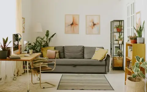 Przytulny salon z biophilic design: kanapa, biurko, rośliny i obrazy tworzą oazę spokoju.