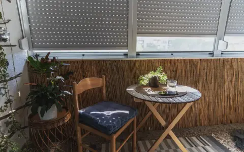 Przytulna loggia z drewnianym krzesłem, stolikiem i roślinami. Idealne miejsce na poranną kawę.