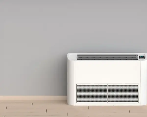 Nowoczesny klimatyzator bez jednostki zewnętrznej, stojący na drewnianej podłodze przy szarej ścianie.