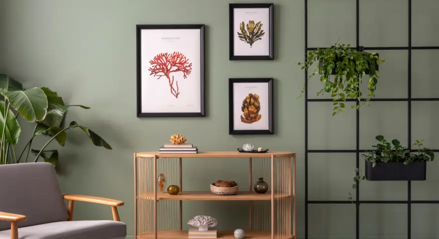 Salon z szarą sofą i drewnianą komodą, ozdobiony obrazami z motywami morskimi. Modne kolory ścian tworzą spokojną atmosferę.