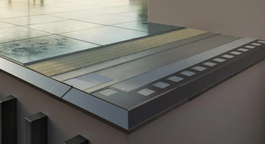 Przekrój nowoczesnej loggii z warstwami izolacji i wykończenia, widoczne płytki i metalowe elementy.