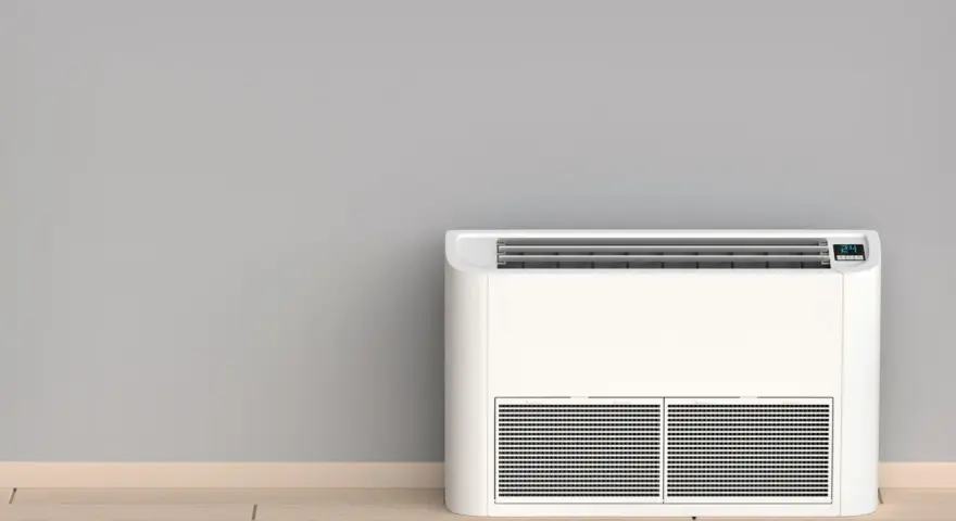 Nowoczesny klimatyzator bez jednostki zewnętrznej, stojący na drewnianej podłodze przy szarej ścianie.
