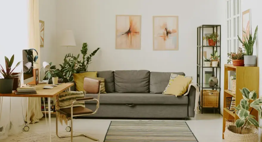 Przytulny salon z biophilic design: kanapa, biurko, rośliny i obrazy tworzą oazę spokoju.