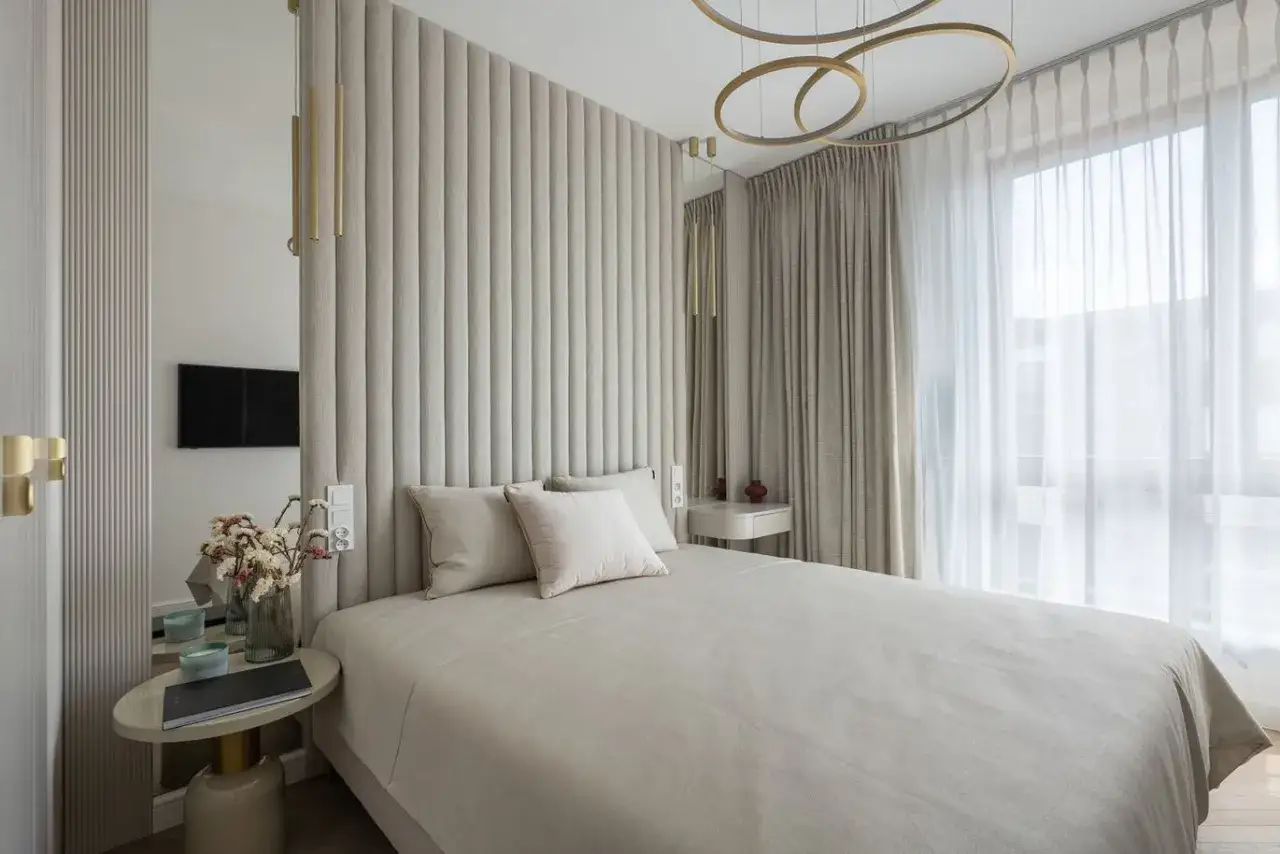 Elegancka sypialnia w beżach. Złote dodatki i delikatne tkaniny tworzą przytulną atmosferę. Jaki kolor pasuje do beżu? Tutaj widzimy, że złoto i jasne odcienie tworzą harmonijną całość.