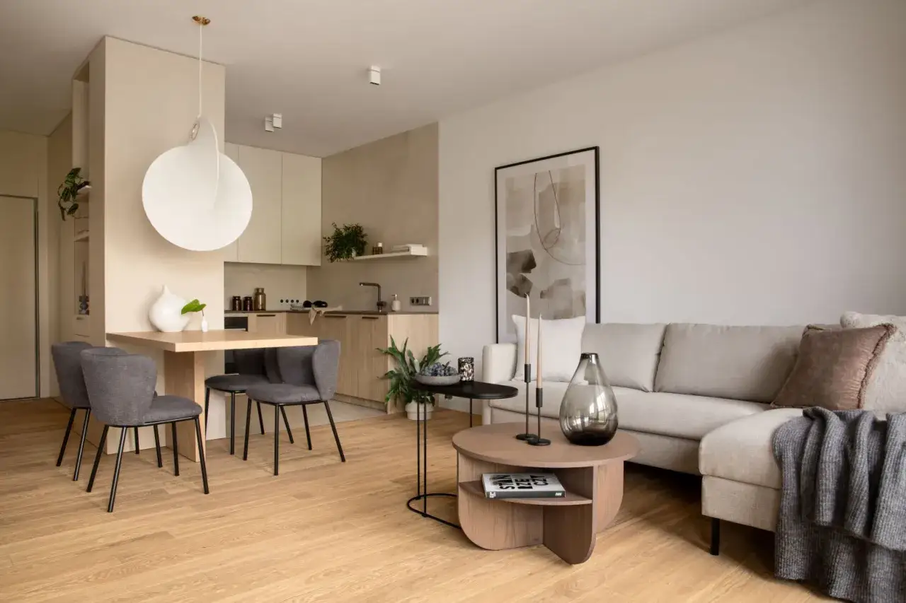 Nowoczesny salon z aneksem kuchennym. Jasne kolory, drewniane akcenty i minimalistyczne meble tworzą przytulną atmosferę. Inspiracja, jak urządzić salon.