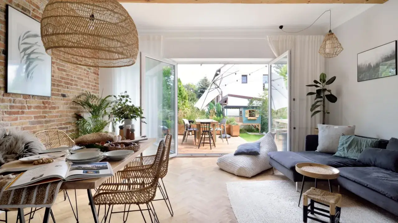 Wnętrze z ceglaną ścianą, drewnianym stołem i roślinami, idealne do relaksu. Biophilic design łączy naturę z domem.